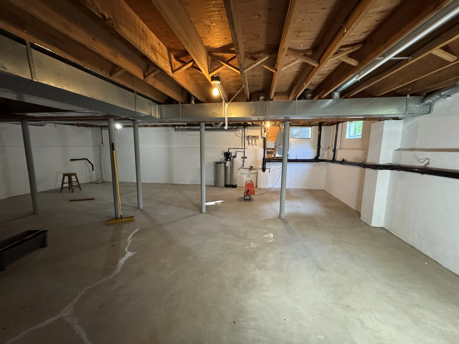 Basement with sealed white walls and bare concrete slab during floor crack repair