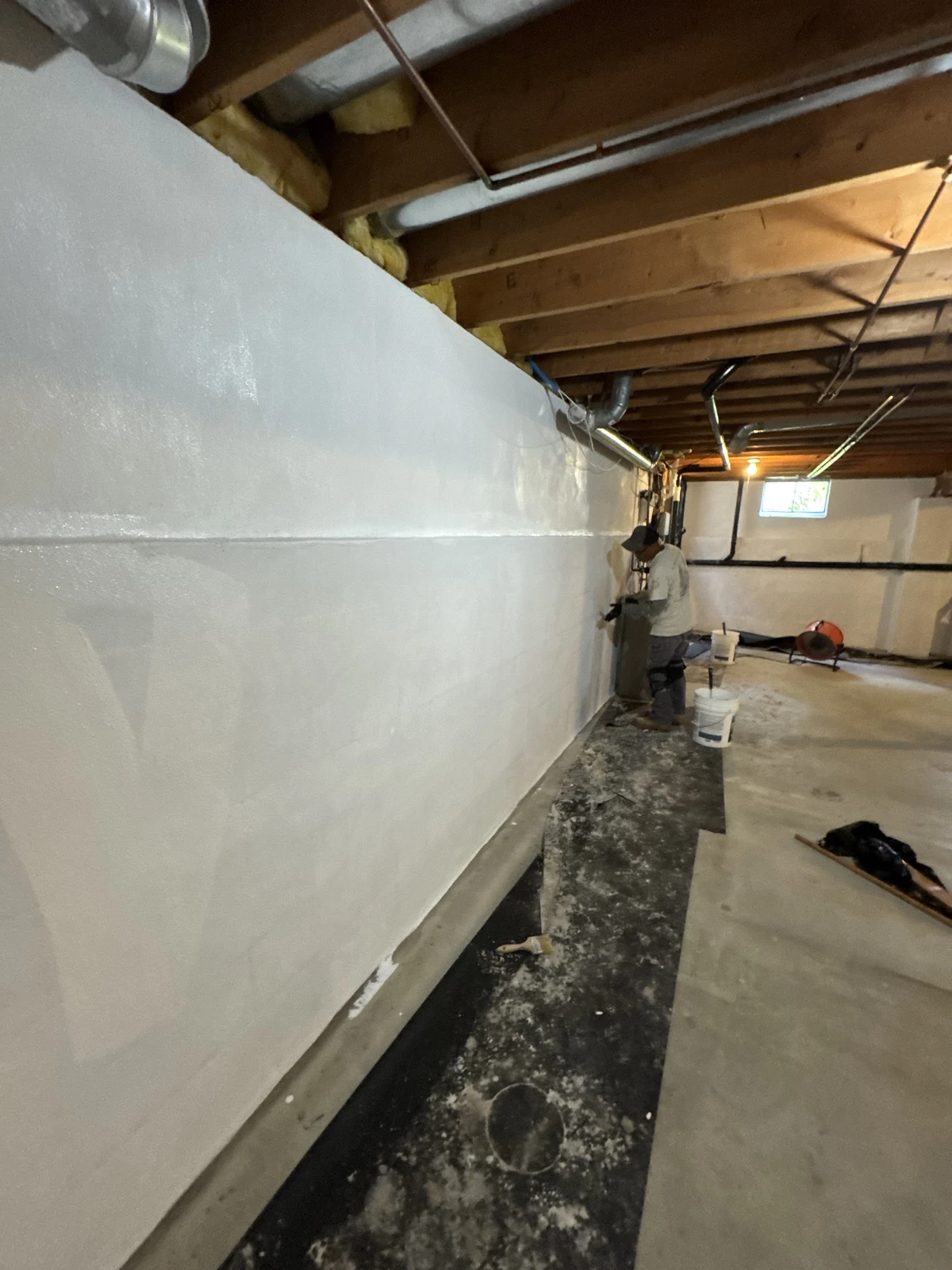 Basement foundation wall sealed with white Coronado Aqua Stop over Tamseal