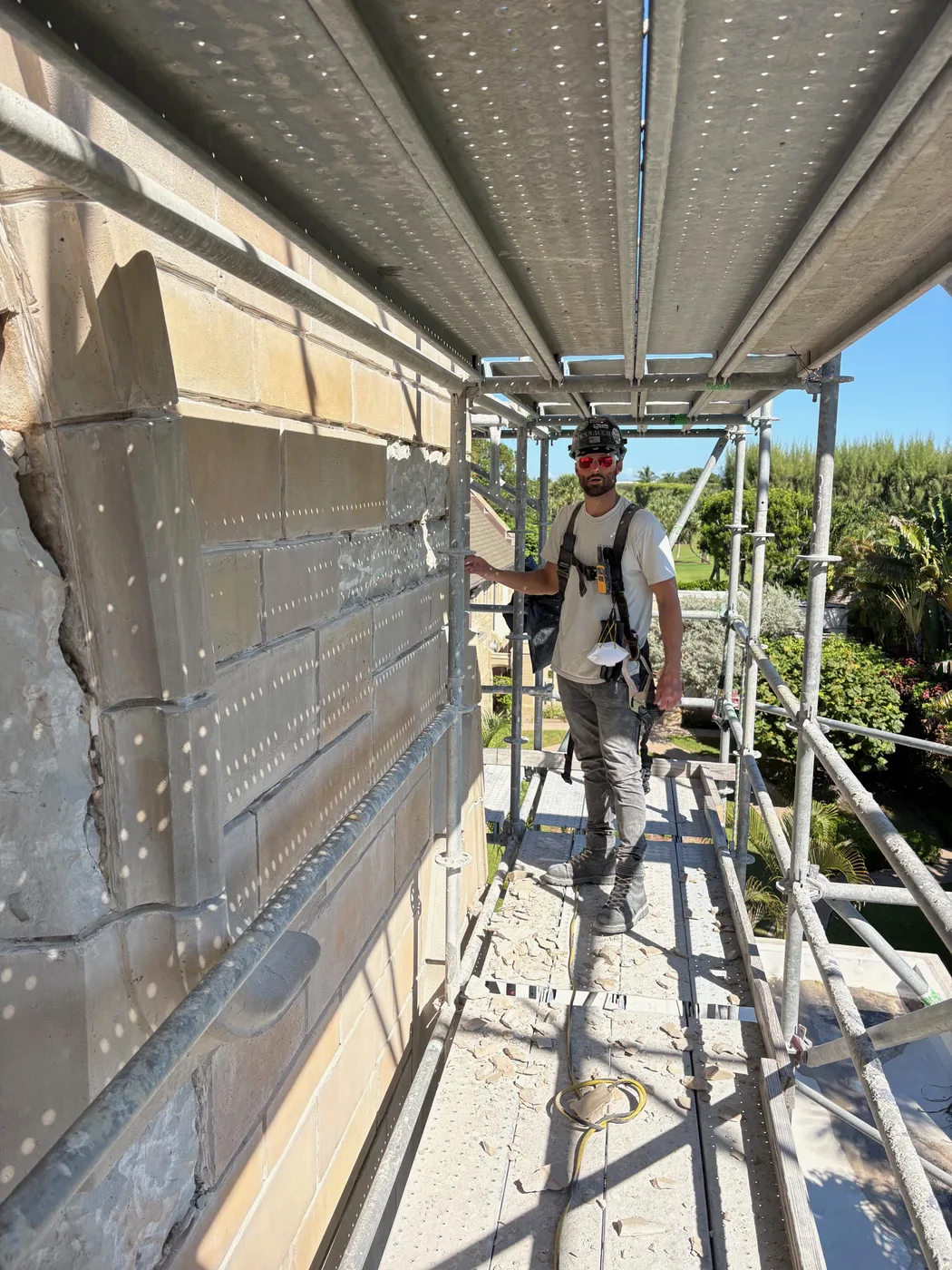 A mason on the scaffolding beside the repaired stone wall at Bethesda-by-the-Sea church in Palm Beach, Florida.